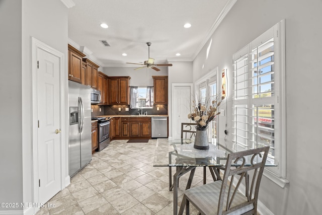 kitchen featuring visible vents, crown molding, decorative backsplash, appliances with stainless steel finishes, and a sink