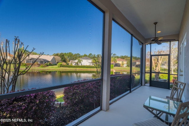 unfurnished sunroom with a residential view, a water view, and ceiling fan