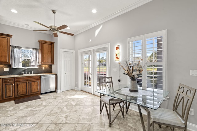 kitchen with backsplash, baseboards, dishwasher, ornamental molding, and a sink