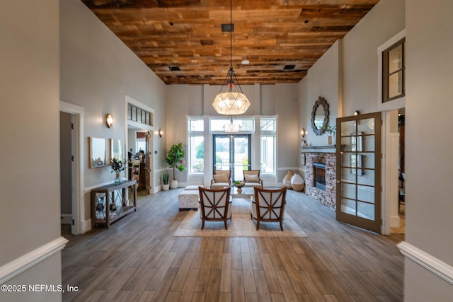 unfurnished dining area featuring wood finished floors, wood ceiling, french doors, and a towering ceiling