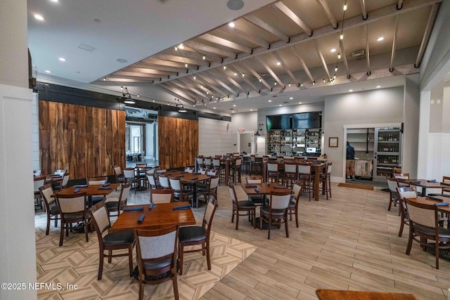 dining area featuring visible vents, track lighting, wood finished floors, a barn door, and wood walls