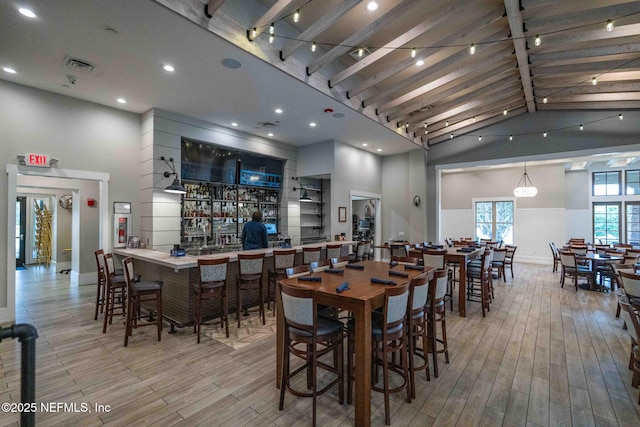 dining space with wood finished floors, visible vents, and high vaulted ceiling