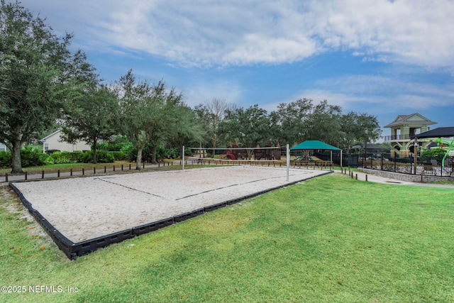 view of property's community featuring a yard, volleyball court, and fence