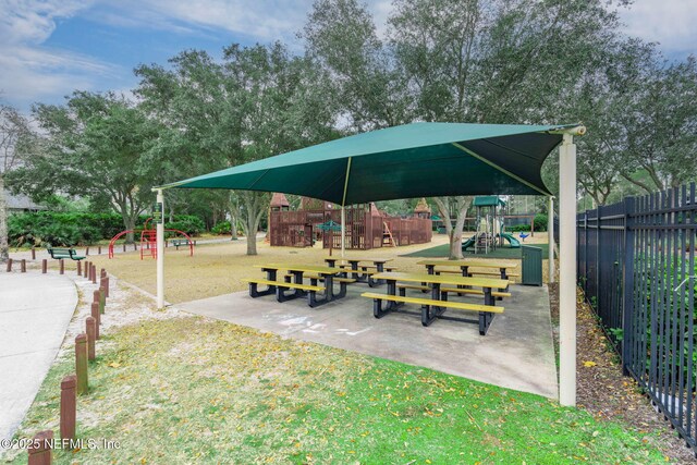 view of community with playground community, a yard, and fence