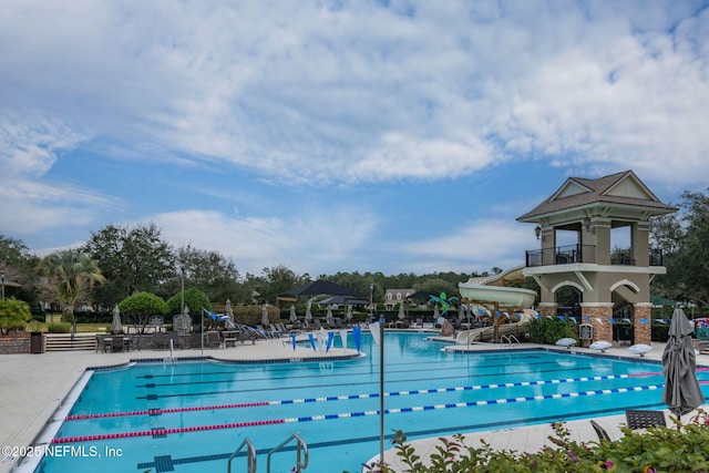 community pool featuring a water slide and a patio area