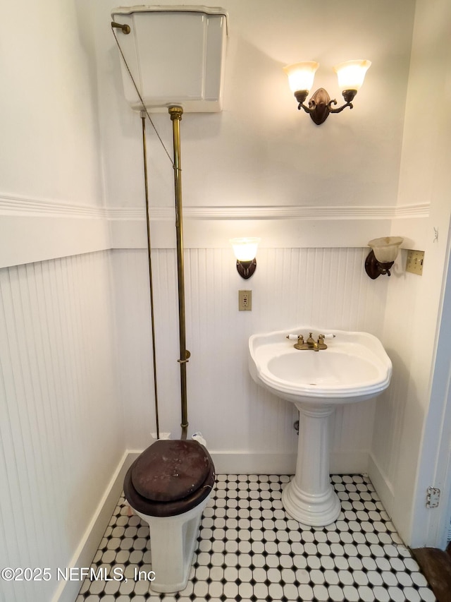 417 N 3rd St, Palatka, FL 32177 - half bathroom with wainscoting, toilet, and a decorative wall