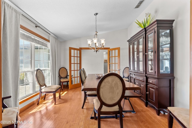 dining space featuring visible vents, a healthy amount of sunlight, french doors, and light wood-style floors