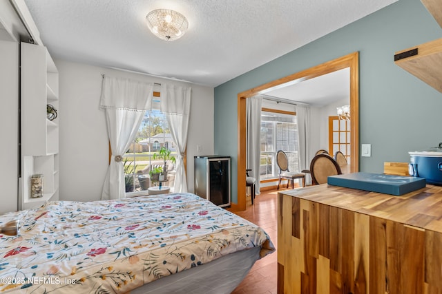 bedroom featuring access to exterior, wine cooler, multiple windows, and a textured ceiling