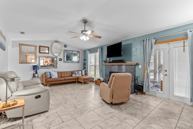 living area featuring visible vents, light tile patterned flooring, a fireplace, ceiling fan, and vaulted ceiling