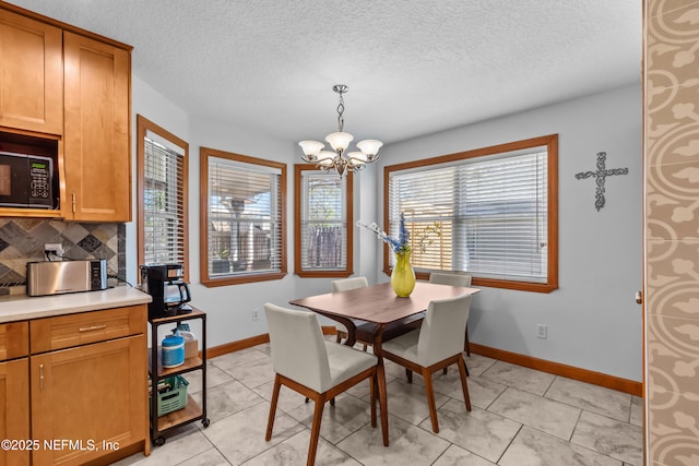 dining area featuring an inviting chandelier, light tile patterned floors, baseboards, and a textured ceiling