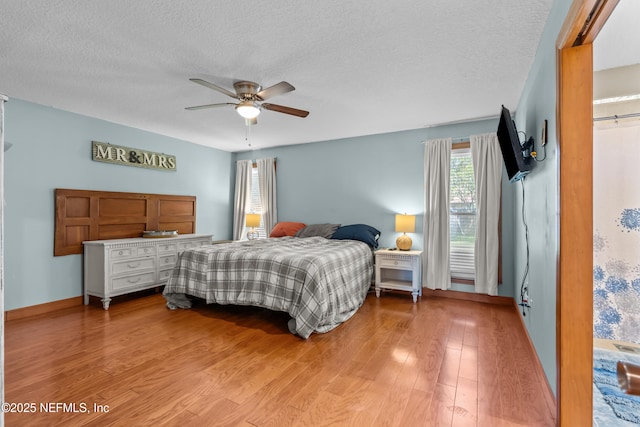 bedroom with light wood-style flooring, a ceiling fan, baseboards, and a textured ceiling