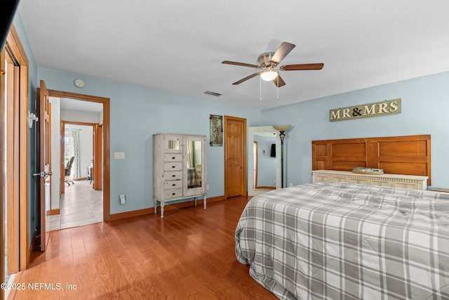 bedroom featuring visible vents, wood finished floors, baseboards, and ceiling fan