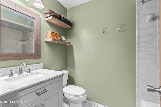 bathroom featuring toilet, tiled shower, and vanity