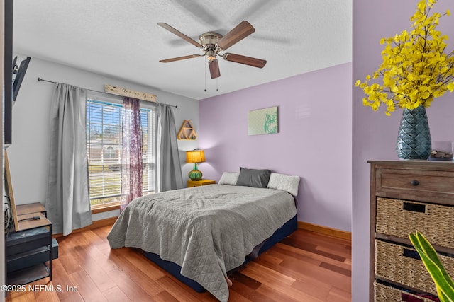 bedroom with a textured ceiling, baseboards, and wood finished floors