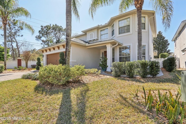 view of front of property featuring stucco siding, driveway, fence, a front yard, and a garage