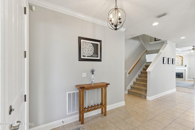 entrance foyer featuring visible vents, ceiling fan with notable chandelier, stairway, a fireplace, and light tile patterned floors