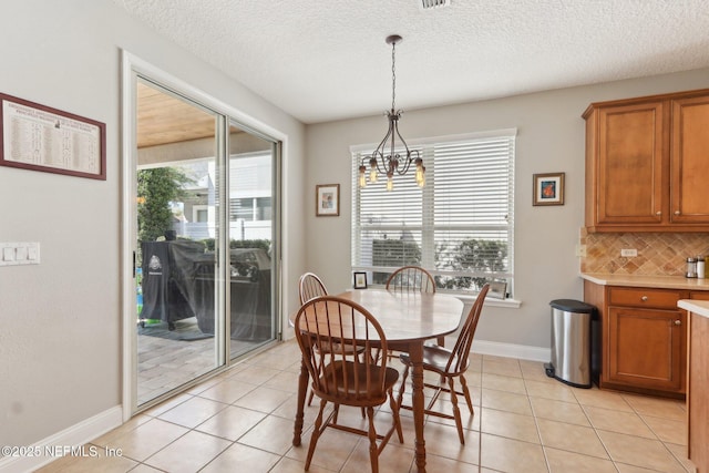 dining room with light tile patterned floors, baseboards, a textured ceiling, and a chandelier