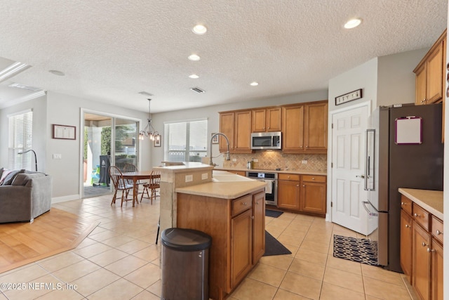 kitchen with decorative backsplash, light tile patterned floors, brown cabinets, and appliances with stainless steel finishes