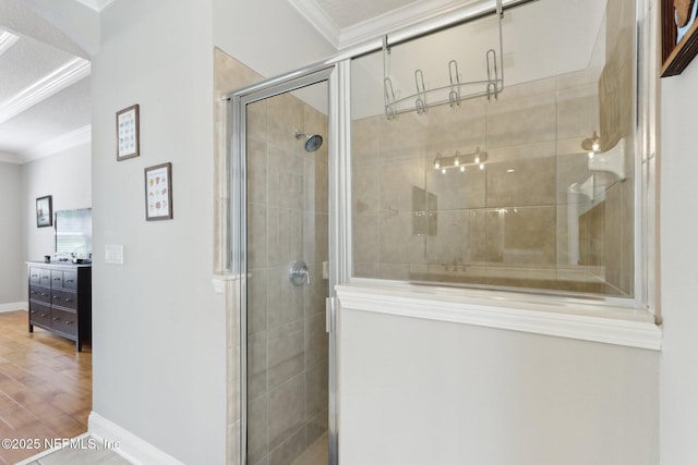 bathroom featuring a shower stall, wood finished floors, baseboards, and ornamental molding