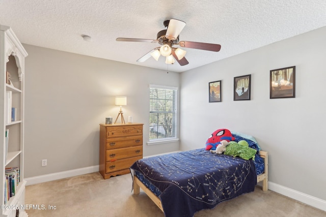 bedroom featuring baseboards, light colored carpet, a ceiling fan, and a textured ceiling