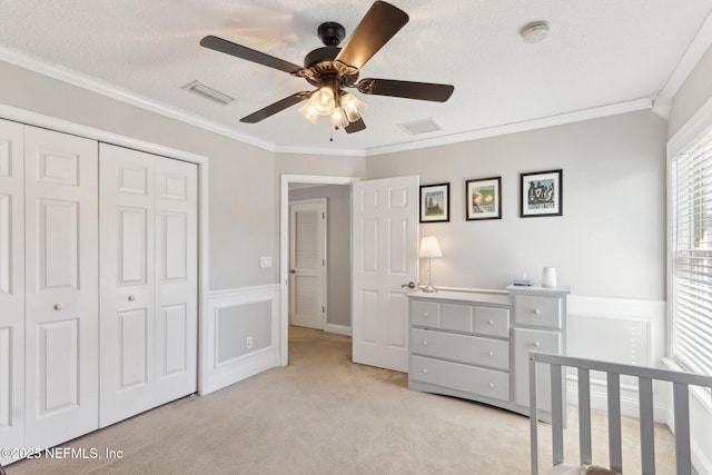 bedroom featuring a textured ceiling, visible vents, a closet, and ornamental molding