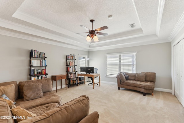 living area with a ceiling fan, visible vents, baseboards, a raised ceiling, and light colored carpet