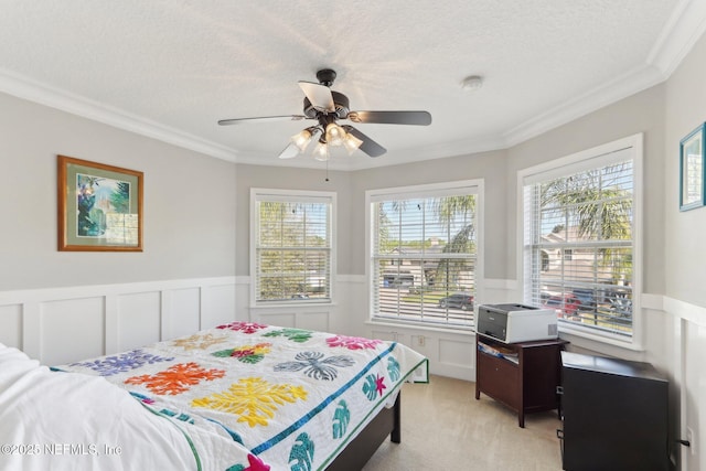 bedroom with wainscoting, light colored carpet, and a textured ceiling