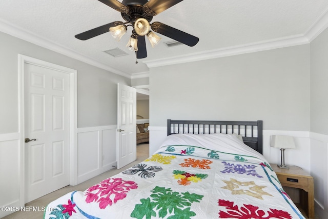 bedroom with crown molding, carpet flooring, visible vents, and a wainscoted wall