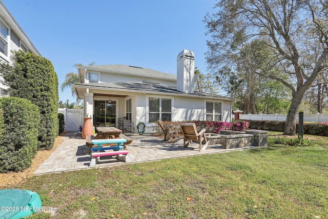 back of property featuring a lawn, a gate, a patio, fence, and a chimney