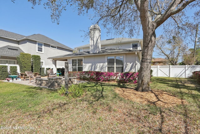 rear view of property featuring a patio area, stucco siding, a lawn, and fence