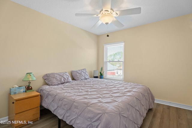 bedroom with a ceiling fan, wood finished floors, and baseboards