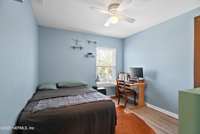 bedroom featuring ceiling fan, wood finished floors, baseboards, and a textured ceiling