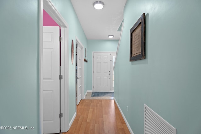 corridor featuring visible vents, light wood-type flooring, and baseboards