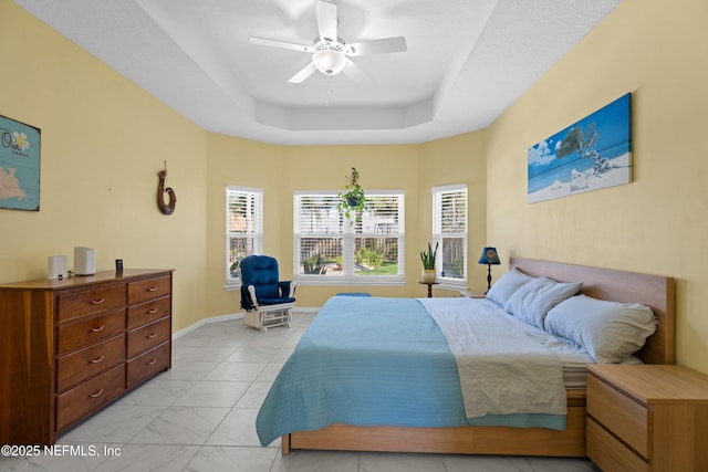 bedroom with marble finish floor, baseboards, a raised ceiling, and ceiling fan