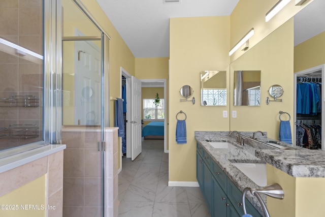 ensuite bathroom featuring baseboards, a stall shower, a sink, marble finish floor, and connected bathroom