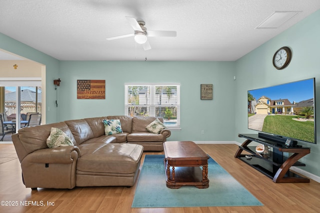 living area featuring visible vents, a textured ceiling, a ceiling fan, and wood finished floors