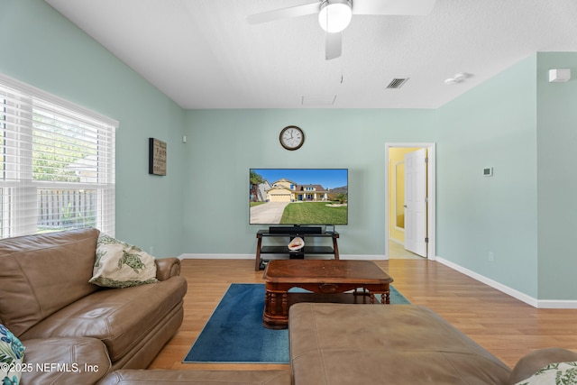 living area with visible vents, baseboards, wood finished floors, and a ceiling fan