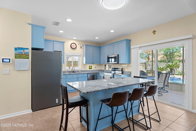 kitchen with light stone counters, visible vents, a breakfast bar, appliances with stainless steel finishes, and blue cabinets