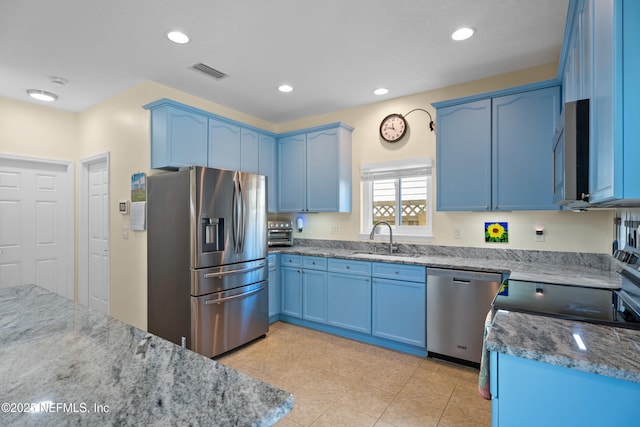 kitchen with light stone countertops, visible vents, blue cabinetry, a sink, and appliances with stainless steel finishes