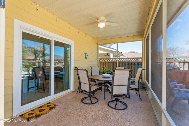 sunroom with rail lighting, a wealth of natural light, and ceiling fan