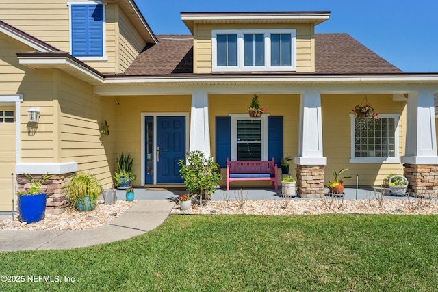 entrance to property with a yard, a porch, and a shingled roof