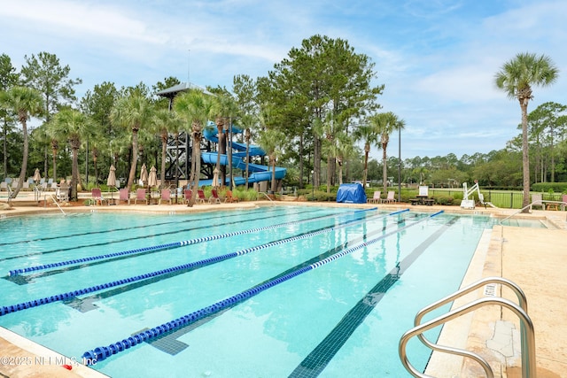 pool with a water slide, a patio, and fence