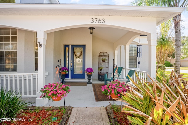 property entrance with stucco siding and a porch