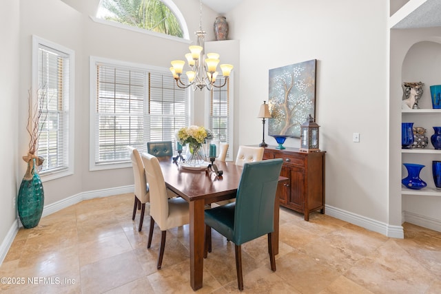 dining area featuring baseboards, a high ceiling, and a chandelier