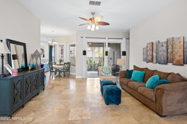 living room with ceiling fan with notable chandelier, visible vents, and baseboards