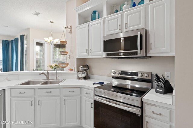 kitchen featuring visible vents, light countertops, appliances with stainless steel finishes, white cabinets, and a sink