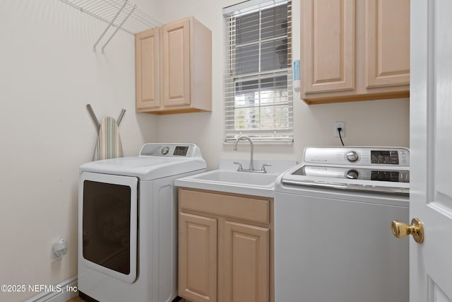 washroom with washing machine and clothes dryer, cabinet space, and a sink