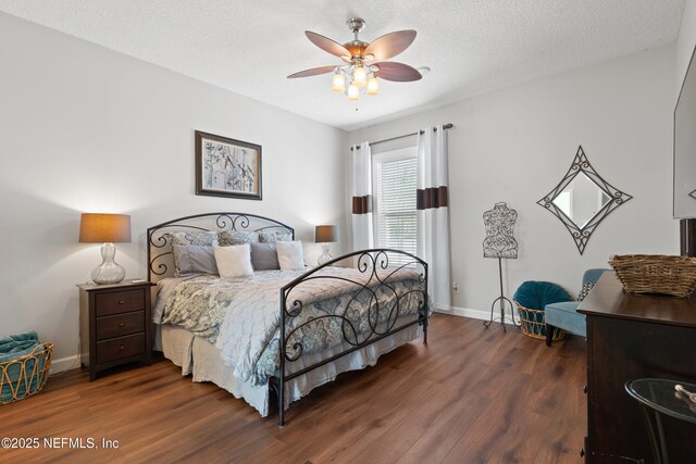 bedroom featuring a ceiling fan, wood finished floors, baseboards, and a textured ceiling