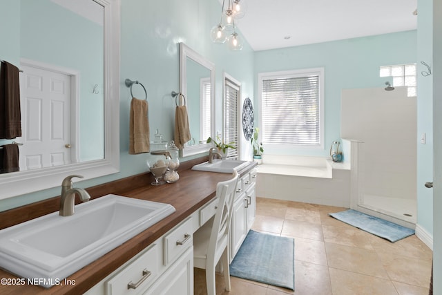 bathroom featuring tile patterned flooring, double vanity, a tile shower, and a sink