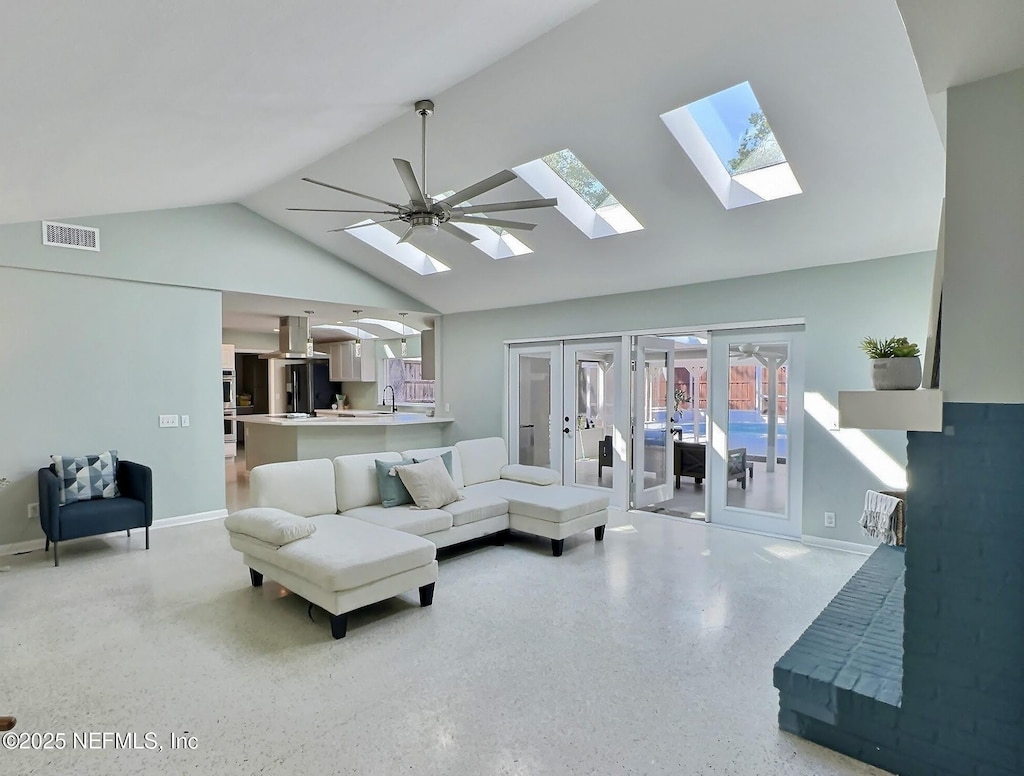 living area with visible vents, high vaulted ceiling, a skylight, french doors, and light speckled floor